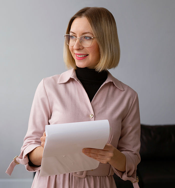 A smiling woman in glasses holding papers, illustrating the different jobs people perform.