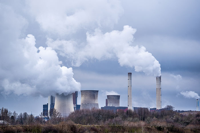 A power plant emitting thick smoke into a cloudy sky, representing one of the weird jobs.