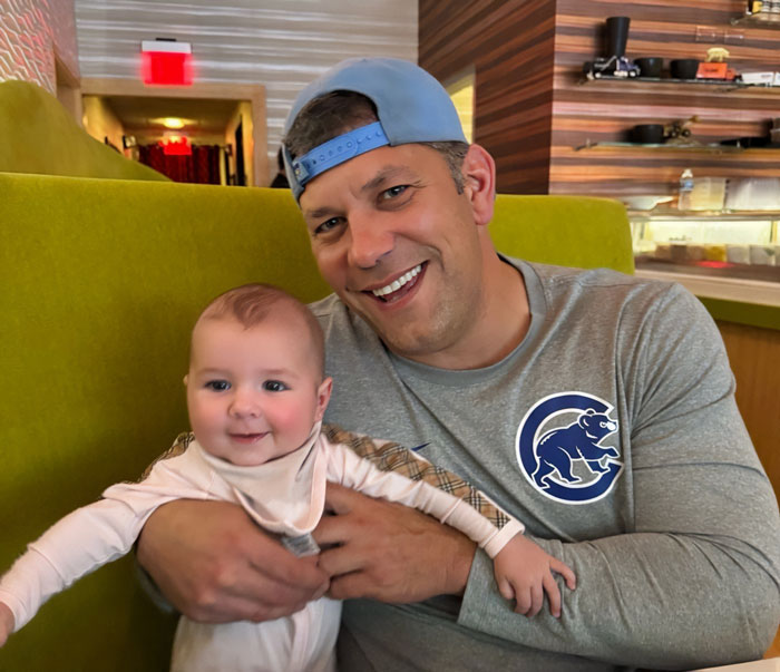 A happy marine vet with a baby, smiling during a family celebration before eating raw oysters. A happy marine vet with a baby, smiling during a family celebration before eating raw oysters.