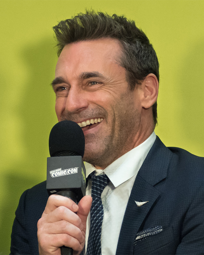 Jon Hamm smiling and holding a microphone, with fans skeptical about Jon Hamm expecting his first child. Jon Hamm smiling and holding a microphone, with fans skeptical about Jon Hamm expecting his first child.