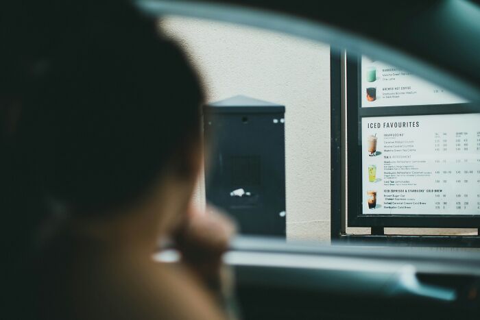 A customer looking at a Starbucks drive-through menu, contemplating what to order, possibly about to say crazy things.