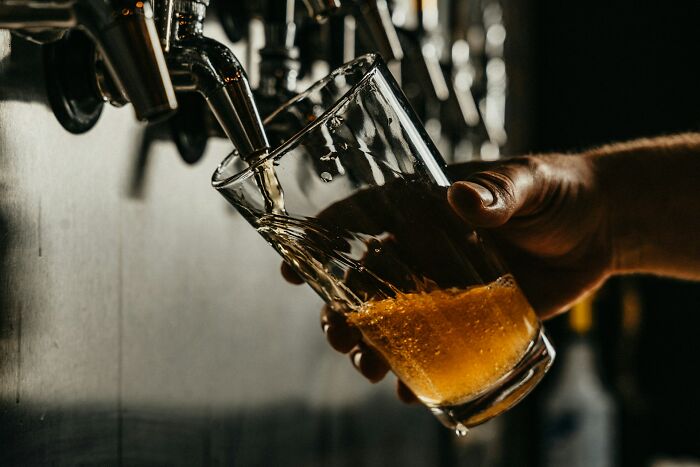 A hand pouring a drink into a glass. This image is likely unrelated to the medical field workers article.