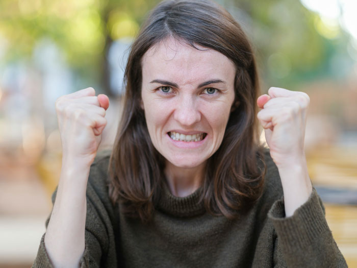 A woman with an angry expression, clenching her fists, representing a Karen in a confrontation about a weapon.
