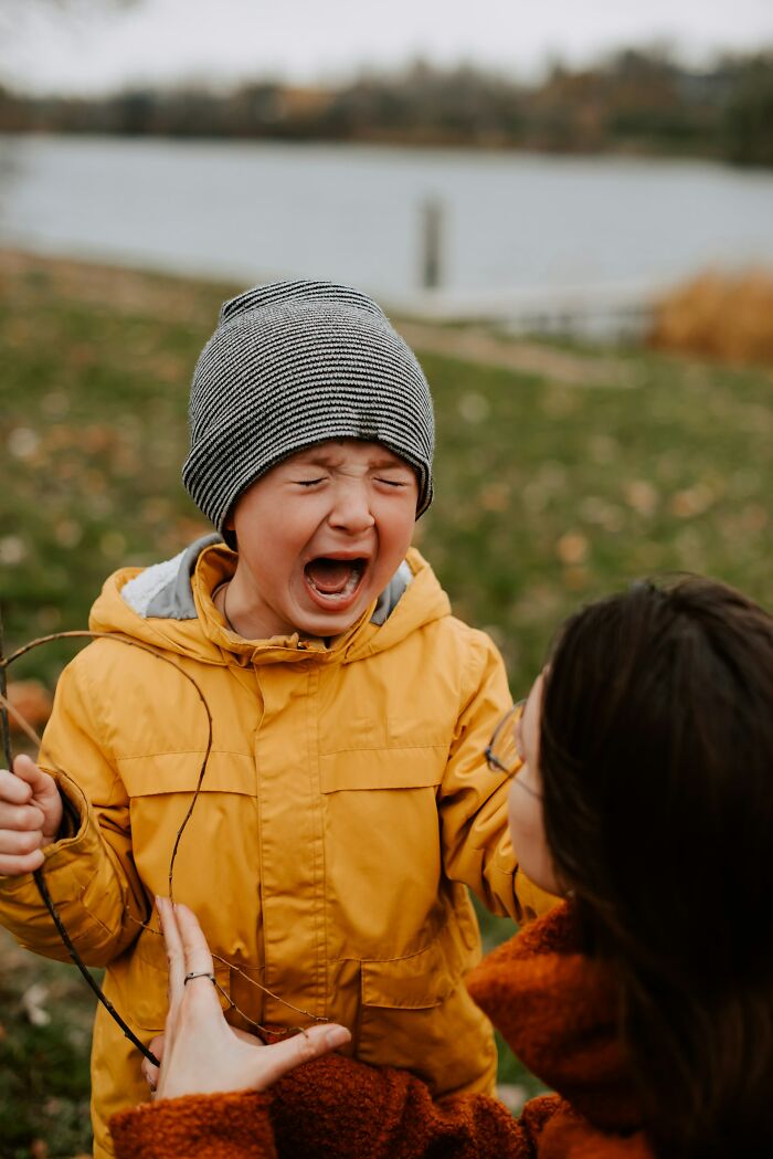 A young boy in a yellow jacket cries out while a woman looks on, discussing a horrible parent situation.