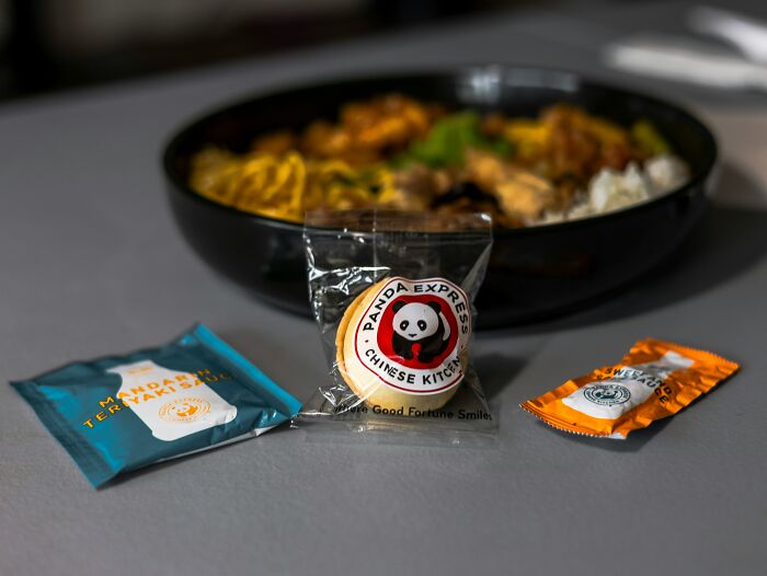 A Panda Express meal with a fortune cookie and sauces, illustrating the variety of food served at a drive-through.
