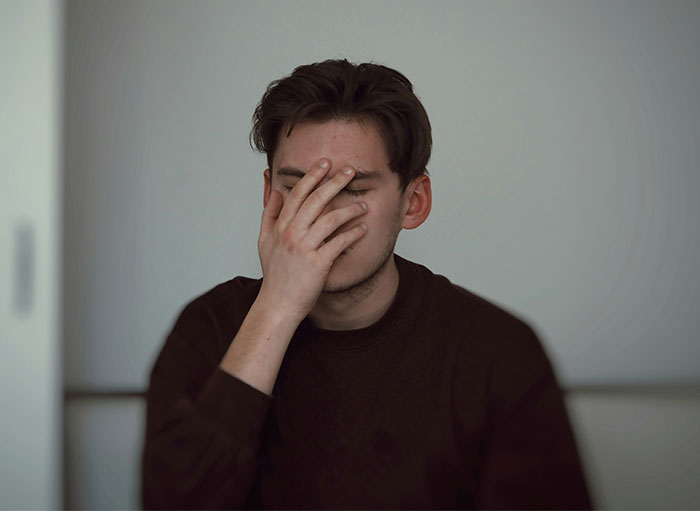 A man with short brown hair, wearing a dark shirt, covers his face with one hand, expressing frustration about landlord issues. A man with short brown hair, wearing a dark shirt, covers his face with one hand, expressing frustration about landlord issues.