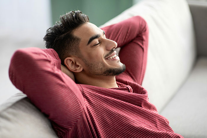 Smiling man relaxing on a couch, representing tenant rights and fighting for heating in winter. Smiling man relaxing on a couch, representing tenant rights and fighting for heating in winter.