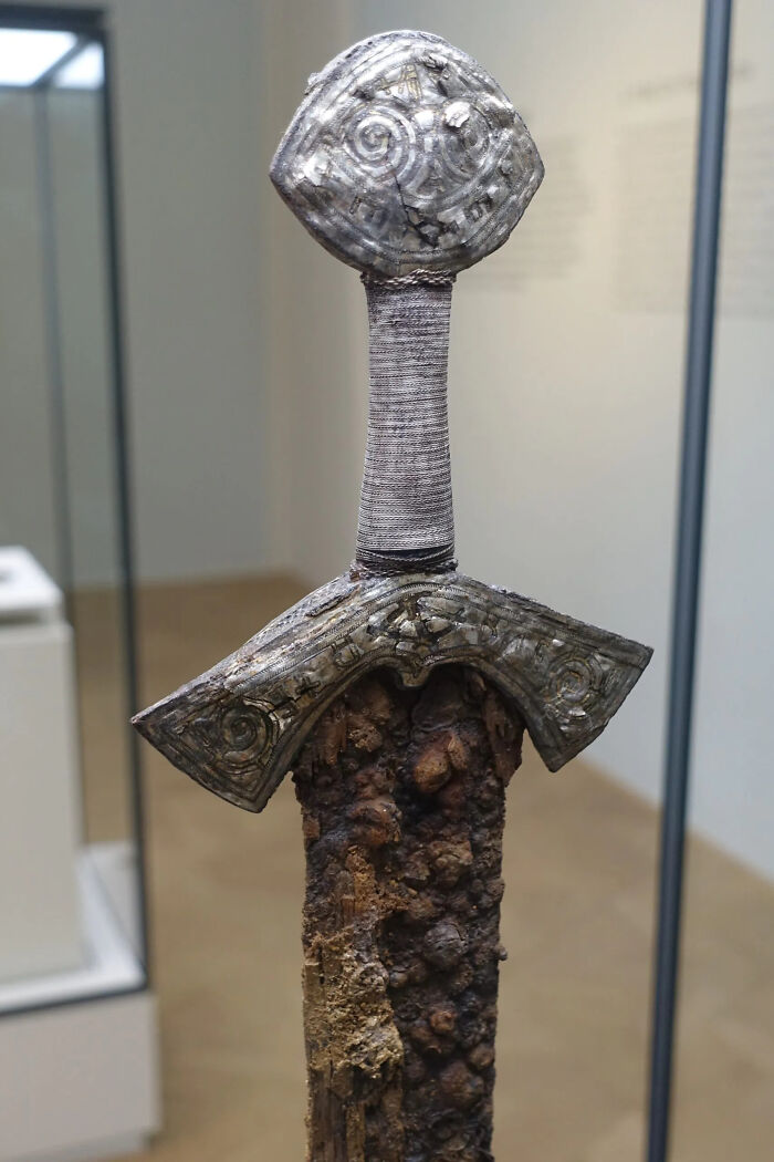 A close-up of a corroded sword hilt and pommel, a surviving historical artifact from ancient times.