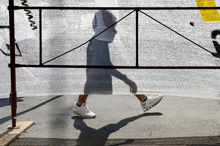 Shadow of a person walking behind a translucent fence, captured as a winning photo in the LensCulture Street Photography Awards.