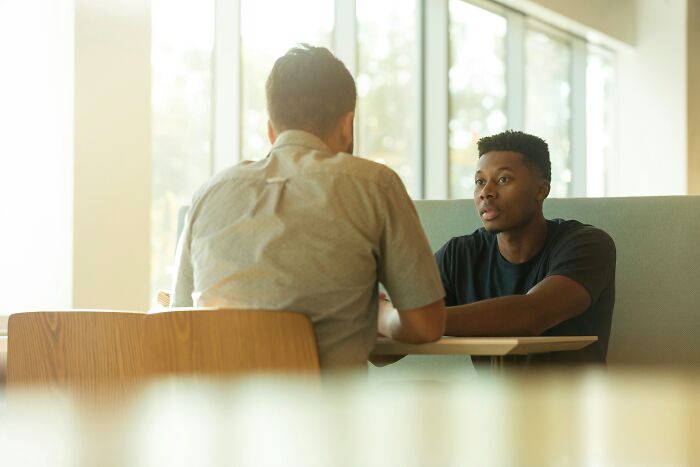 Two men having a serious conversation about work drama stories.