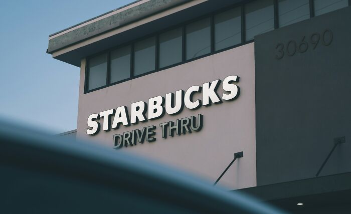A Starbucks drive-through sign against a blue sky, where customers said crazy things that employees could hear.