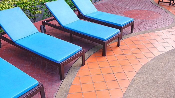 Empty resort lounge chairs in a row with vibrant blue cushions, ready for guests.