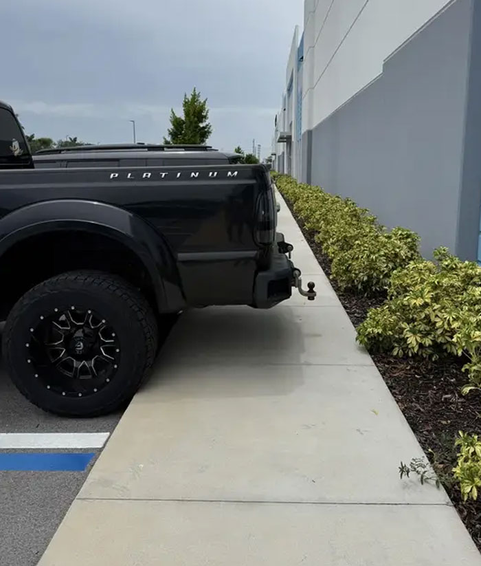 A black pickup truck parked over a sidewalk, demonstrating entitled folks ignoring pedestrian space.