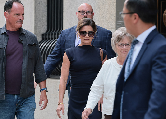 Luigi Mangione case update: Group of individuals, including a woman in sunglasses and a dark dress, walking outdoors. Luigi Mangione case update: Group of individuals, including a woman in sunglasses and a dark dress, walking outdoors.