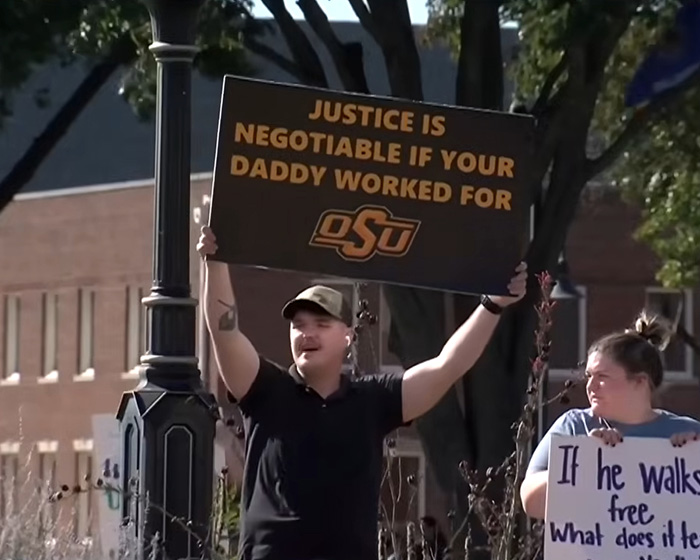A protester holds a sign about justice being negotiable, related to the Oklahoma teen case.