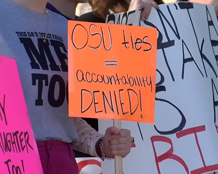 A sign at a protest stating OSU ties equal accountability denied in the Oklahoma teen case.