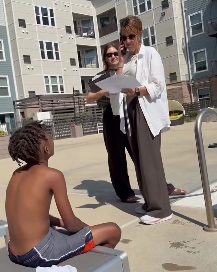 A woman on the phone confronts a Black dad with kids at a pool, with another woman watching. A woman on the phone confronts a Black dad with kids at a pool, with another woman watching.