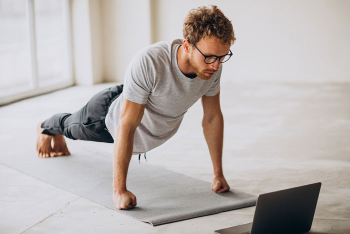 Man performing pushups with a laptop, highlighting the mental shift and consistent effort over a year. Man performing pushups with a laptop, highlighting the mental shift and consistent effort over a year.