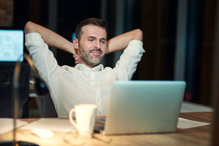 Man at work, not showing up for years, caught when employer tries to celebrate him, smiling at laptop. Man at work, not showing up for years, caught when employer tries to celebrate him, smiling at laptop.
