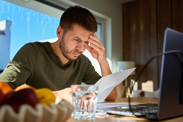 Man showing up to work for 6 years is caught, looking distressed at a document. Man showing up to work for 6 years is caught, looking distressed at a document.