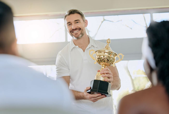 Man holding a trophy, being celebrated by his employer after not showing up to work for 6 years. Man holding a trophy, being celebrated by his employer after not showing up to work for 6 years.