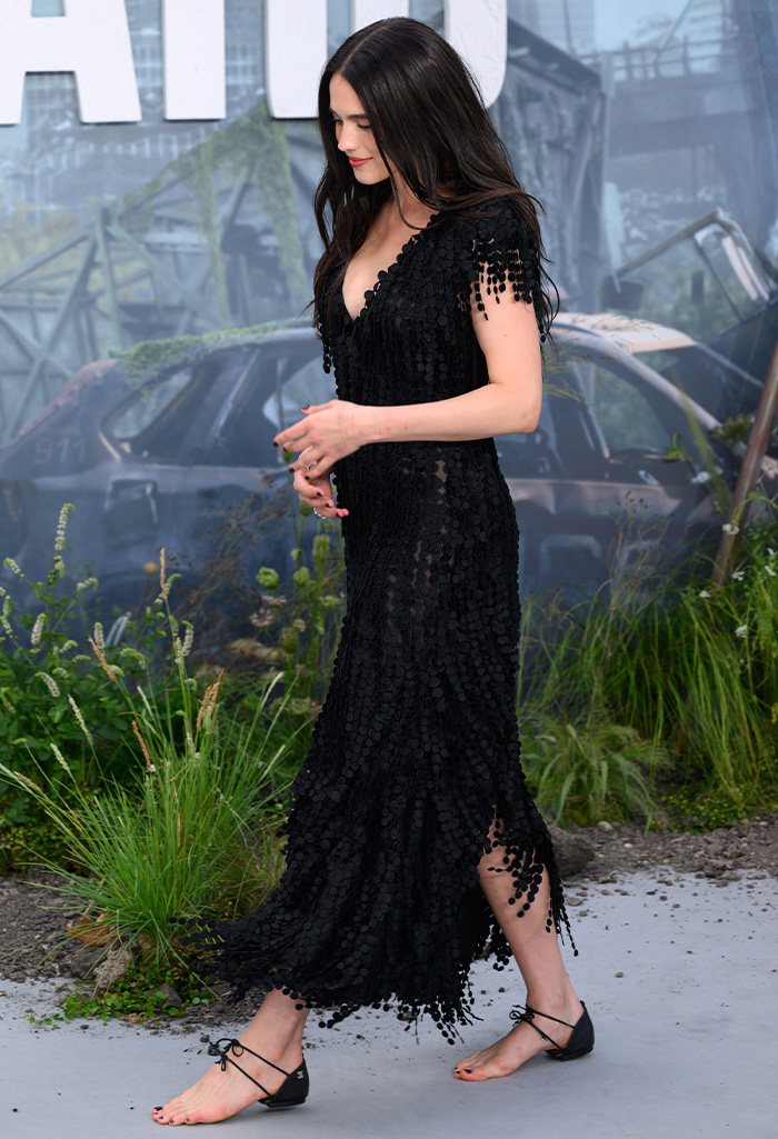 Margaret Qualley walking, showcasing her barefoot sandals and drawing fashion scrutiny.