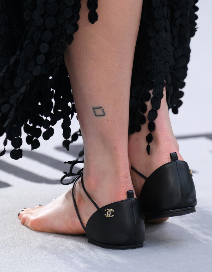Close-up of Margaret Qualley's feet wearing $3K 'barefoot' sandals with ankle straps and a black heel.
