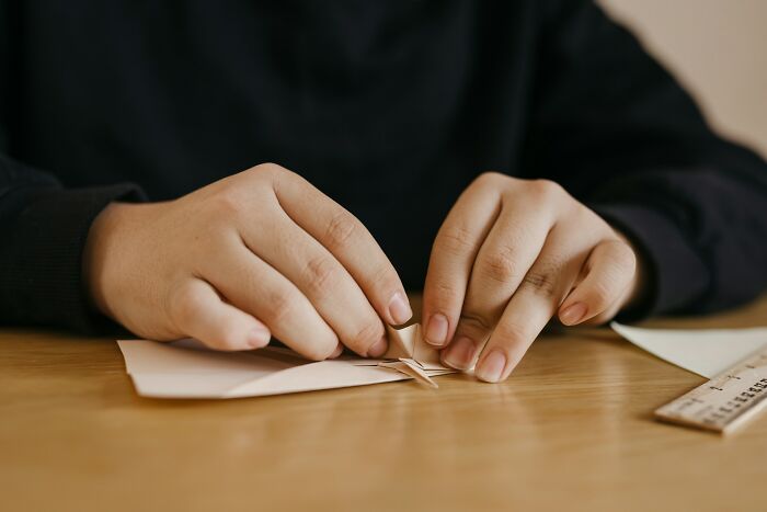 Hands meticulously folding paper, demonstrating a precise process related to scientific facts.