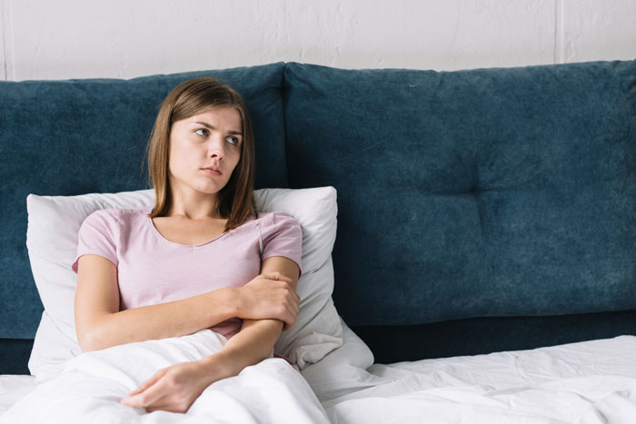 Woman in bed, looking troubled, reflecting a husband mourning his marriage after wife opened it for a colleague.