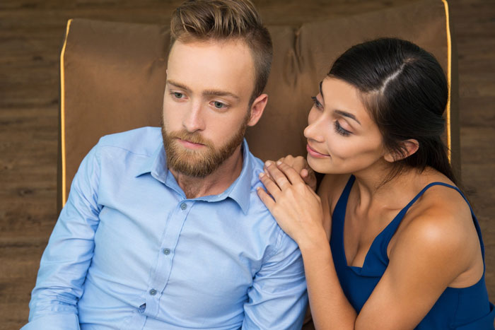 A man looking distressed with a woman comforting him, mourning his marriage after realizing his wife opened it for a colleague.