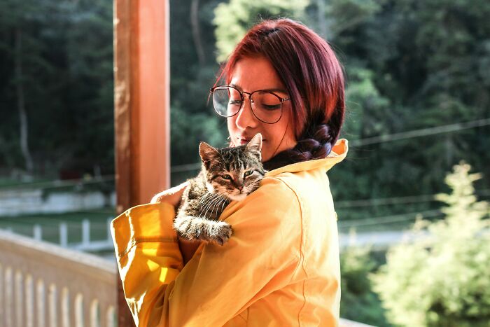 A woman gently holding a cat, suggesting comfort and the importance of mental health away from relationship red flags.