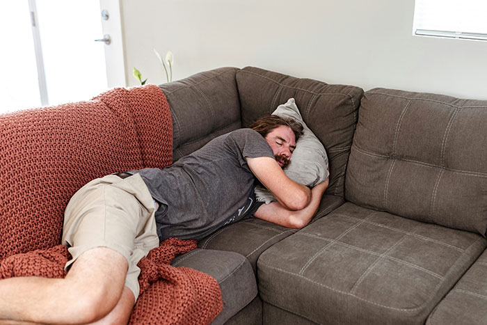 Man sleeping on a couch, illustrating the viral take on mental load in relationships. Man sleeping on a couch, illustrating the viral take on mental load in relationships.
