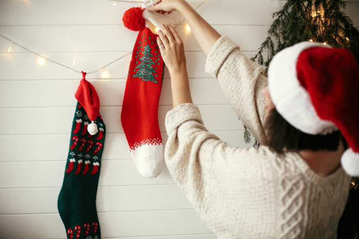 A person in a Santa hat hanging Christmas stockings, symbolizing Future Grandma's plans for baby's first Christmas. A person in a Santa hat hanging Christmas stockings, symbolizing Future Grandma's plans for baby's first Christmas.