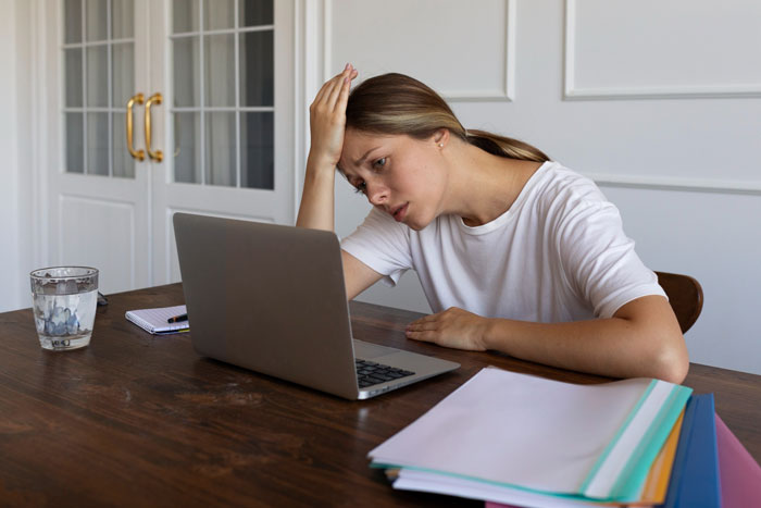 A woman looks frustrated and upset at her laptop, experiencing friendship dispute and hurtful messages. A woman looks frustrated and upset at her laptop, experiencing friendship dispute and hurtful messages.
