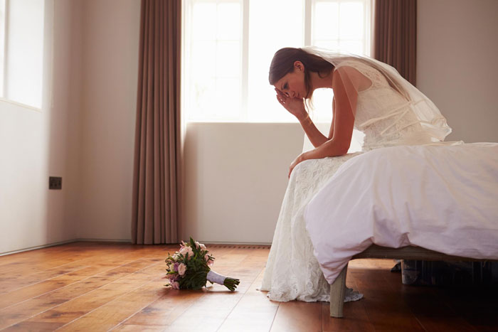 Sad bride, alone on a bed, bouquet on the floor, after a friendship ends. Sad bride, alone on a bed, bouquet on the floor, after a friendship ends.