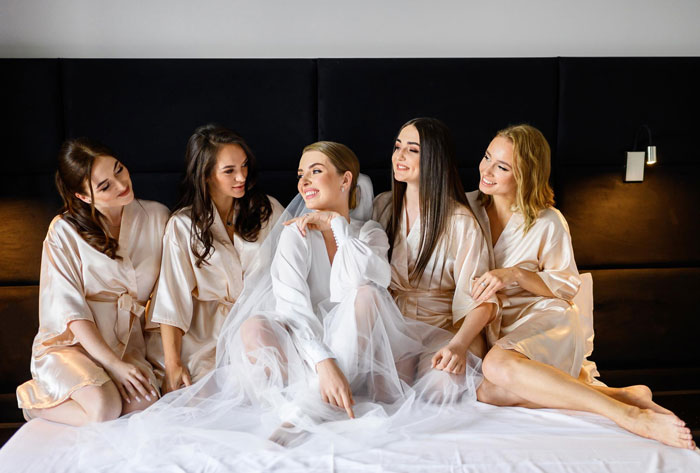 A happy bride and her best friends in robes, celebrating at a bachelorette date. A happy bride and her best friends in robes, celebrating at a bachelorette date.