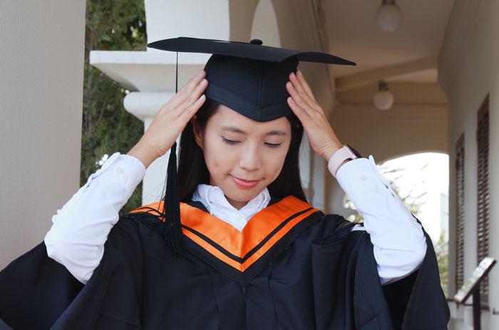 A proud daughter poses in her cap and gown after her surprise graduation BBQ. A proud daughter poses in her cap and gown after her surprise graduation BBQ.