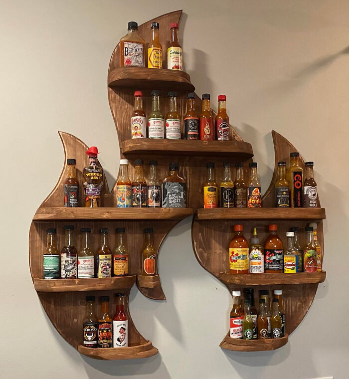 A DIY home project display shelf shaped like a flame, filled with hot sauce bottles, demonstrating you dont need a huge budget.
