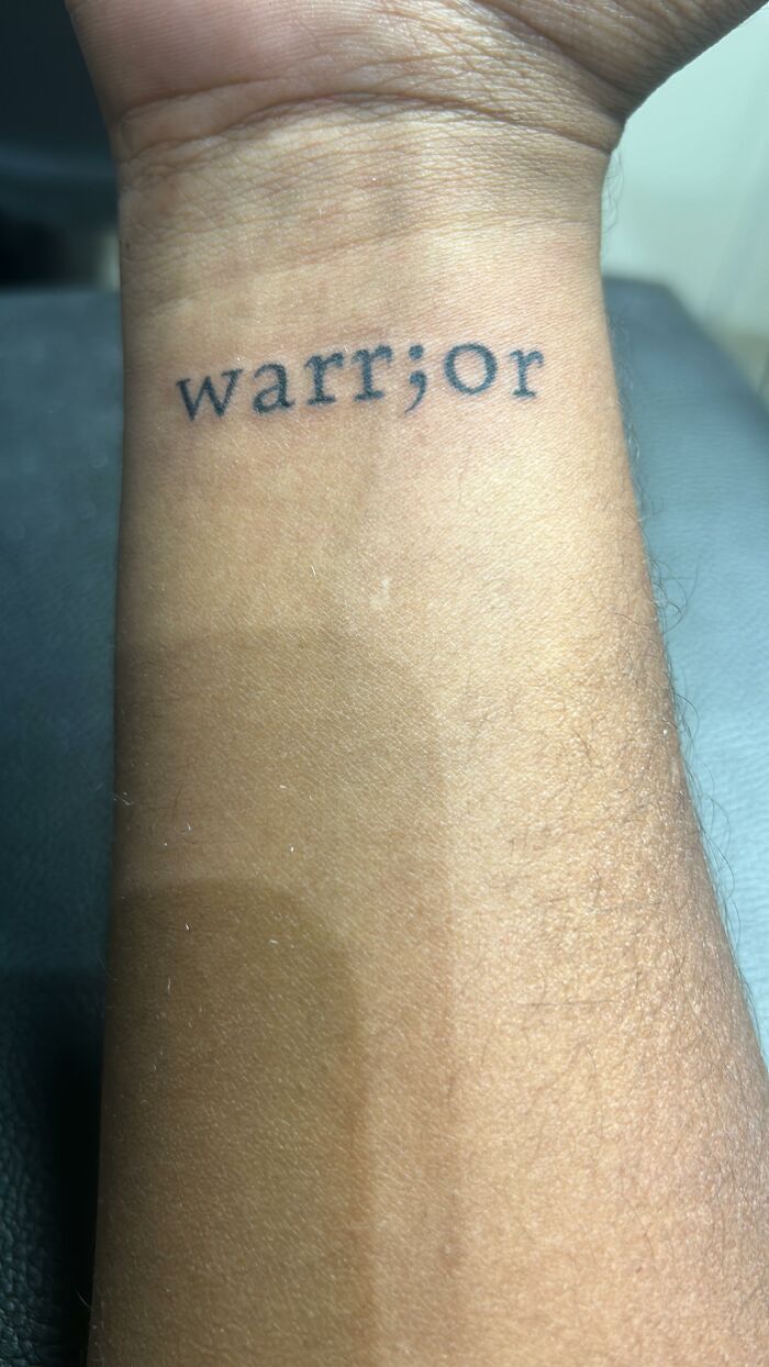 A warrior tattoo with a semicolon, illustrating a powerful story of resilience on the forearm.