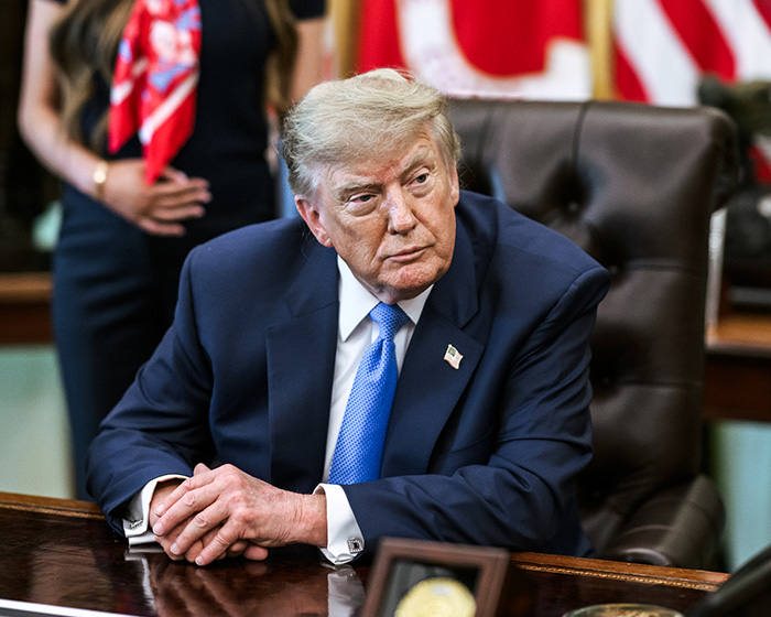 Trump looking forward, with the mystery woman behind him, making a strange gesture.