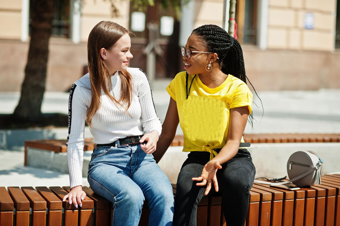 Two young women, best friends, talking on a bench during a family vacation. In-laws caused a tantrum. Two young women, best friends, talking on a bench during a family vacation. In-laws caused a tantrum.