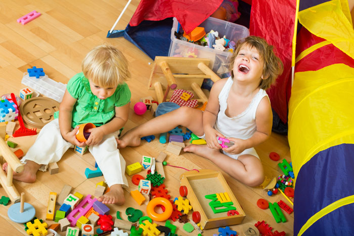 Two young children playing with toys on the floor, symbolizing the kids during a family vacation with their best friend. Two young children playing with toys on the floor, symbolizing the kids during a family vacation with their best friend.