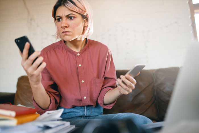 A woman on family vacation looking shocked while holding two phones, confused by her in-laws tantrum. A woman on family vacation looking shocked while holding two phones, confused by her in-laws tantrum.