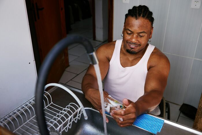A man in a wheelchair washing dishes in a kitchen sink, illustrating a truth of being married.