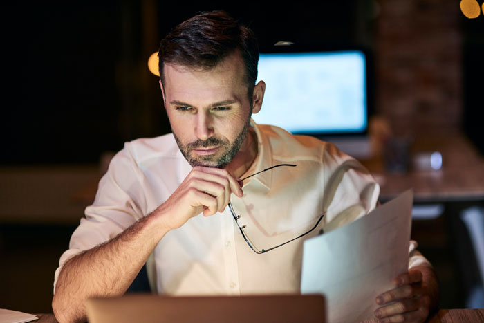 A man, disturbed new parent, thoughtfully looking at documents and a laptop, planning to use his rude neighbor's illegal antenna. A man, disturbed new parent, thoughtfully looking at documents and a laptop, planning to use his rude neighbor's illegal antenna.