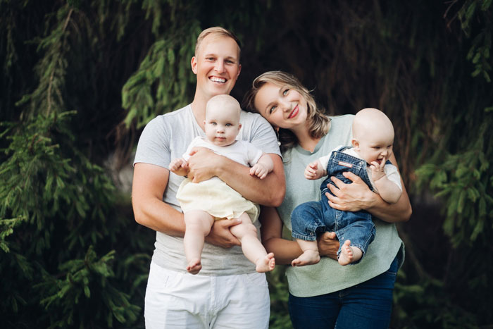 A happy couple, new parents, holding their two infant babies. This image shows new parents and their children. A happy couple, new parents, holding their two infant babies. This image shows new parents and their children.