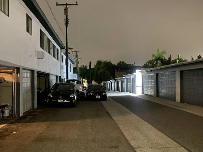Several cars poorly parked in a narrow alleyway at night, showing common sense parking problems.