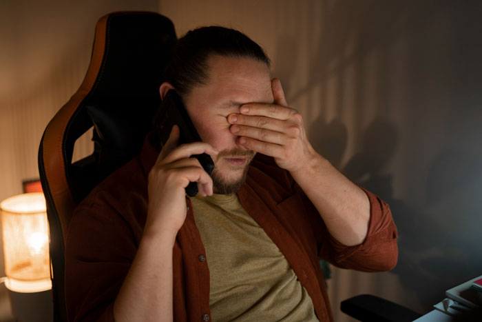 A man talking on the phone, covering his face, fearing for his life due to neighbor's behavior.
