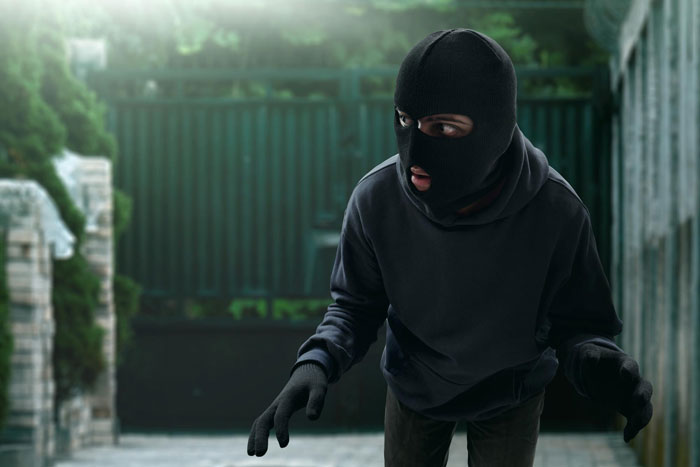 Image of a person in a black ski mask and hoodie, hands gloved, looking alarmed. Represents new neighbor's eerie behavior.