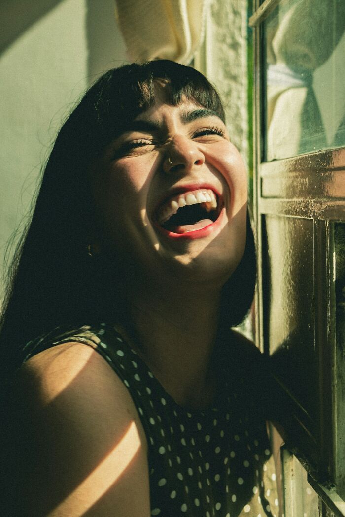A laughing woman with a nose ring, sunlight on her face, portraying interesting neighbors.